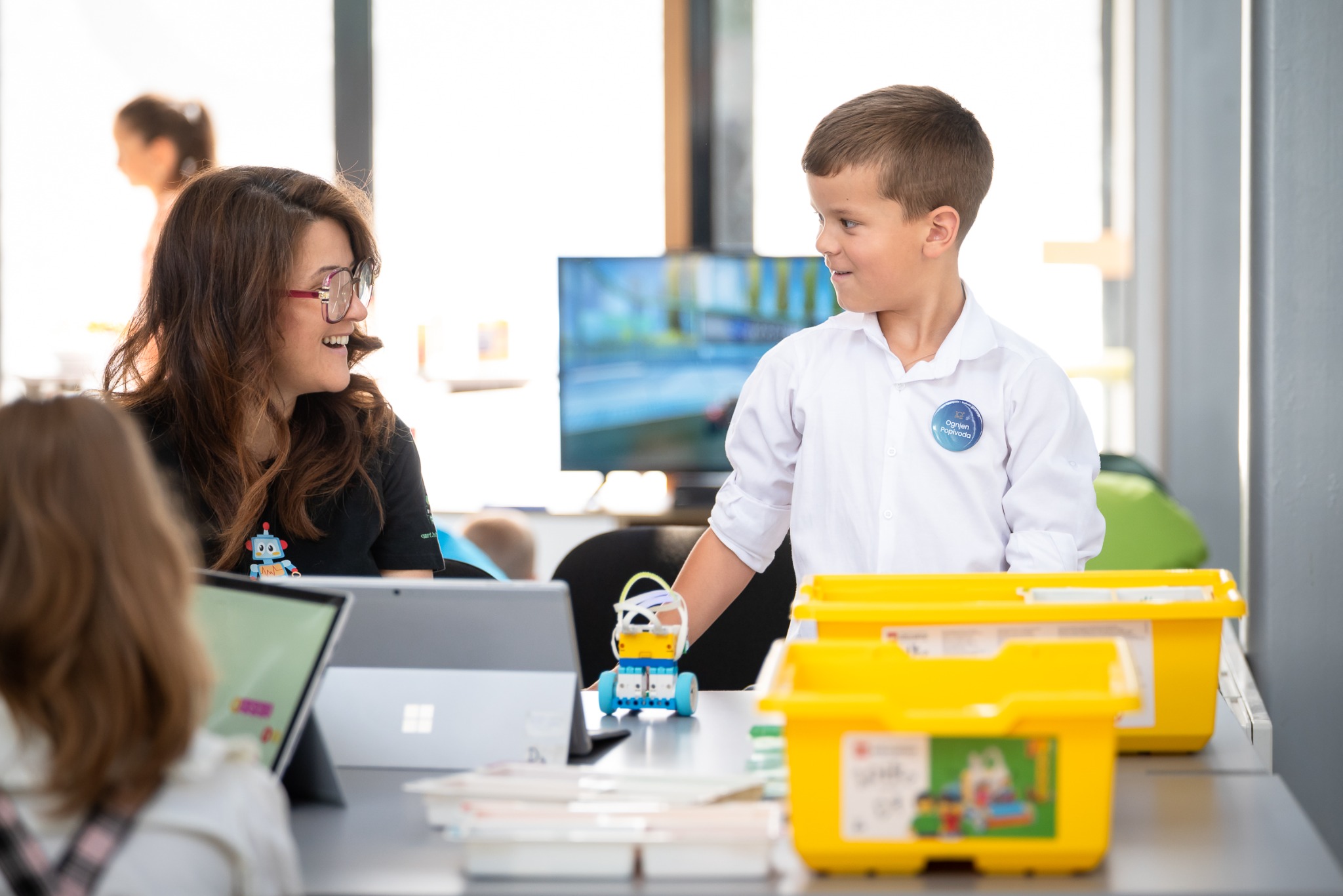 Edukatorica i dječak razgovaraju uz LEGO robota na radionici Dvorišta.